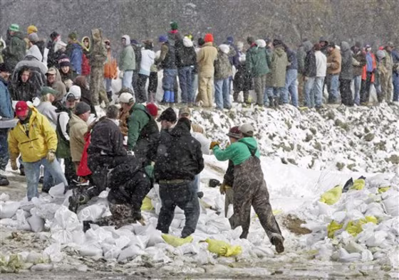 Snow flurries fall as scores of volunteers build up a dike to hold back the rising Red River flood waters in Fargo, N.D. in this&nbsp;March 27, 2009 file photo. During last spring's flooding, a statewide 211 number established to take calls for social services fielded more than 40,000 inquiries. Now the number may go out of business in most of the state.